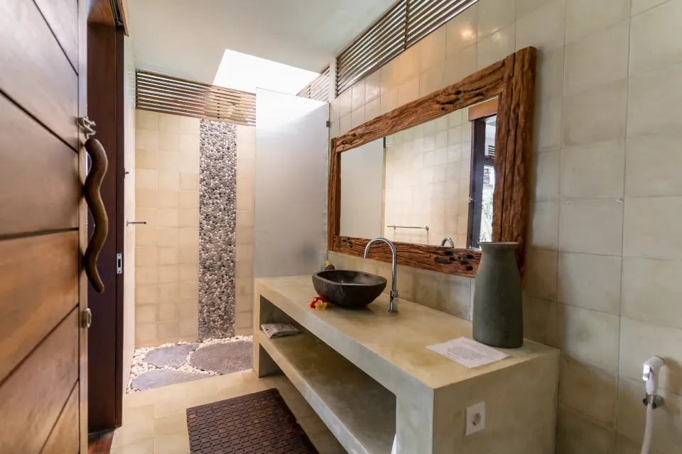 A stone washbasin beside an open courtyard shower