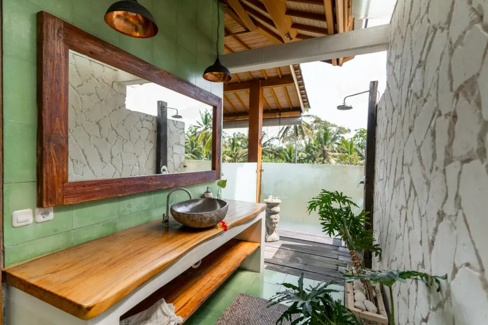 An open-air bathroom with a stone basin and garden outlook